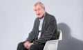 Writer Julian Barnes, sitting in white chair against blue background, Dec 2022