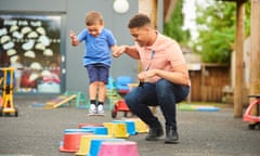 A man plays with a child at a playground at a nursery