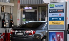 A car at a service station and signage indicating different fuel types available