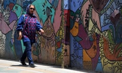 An Iranian woman wearing a hijab walks past a mural.