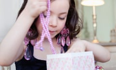Young girl takes a bright pink necklace from a jewellery box