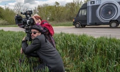 Still from the movie Faces Places, a travel documentary showing the two directors and stars with a camera in a field.