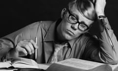 A black and white image of a young man in the 1970s with books open in front of him