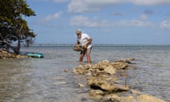 Frank Woll stands in ankle-deep seawater, building a retaining wall.