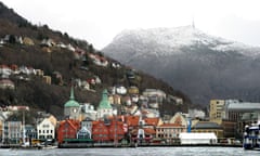 Shop fronts and Hanseatic houses fringe the coast in Bergen. Mountains behind