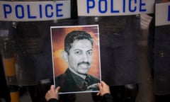 A protester holds a picture of the human rights activist Abdulhadi al-Khawaja in front of riot police