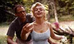 Arthur Miller and Monroe in 1957, leaning on a wooden fence in the sunlit countryside, she holding daisies