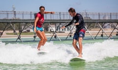 Surfer and instructor ride a wave at NLand Surf Park, Austin Texas