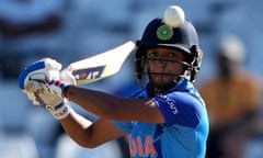 A female cricketer swinging her bat at a ball