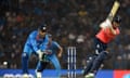 Eoin Morgan plays a shot as India’s MS Dhoni looks on