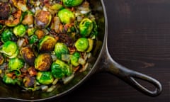 A cast iron skillet with Brussels Sprouts over a dark table top
