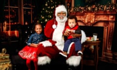 A Black Santa Claus with two kids on his lap.