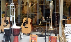 The front window of a music shop, showing instruments including guitars, drums, a saxaphone and a recorder