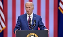 Man in blue suit on stage in front of American flag