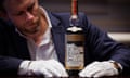 Jonny Fowle regards a bottle of The Adami Macallan with a label designed by Valerio Adami while holding its base with white gloves