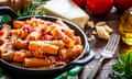 Pasta in a cast iron pan shot on rustic wooden table.