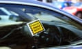 A parking charge notice attached to the window of a car in a car park