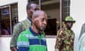 Man in green and blue T.shirt beside two other men, one in army camouflage jacket,  outside building