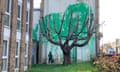 Mural dhow a lifesize depiction of a woman holding a pressure washer, having apparently sprayed green paint up the side of a block of flats