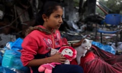 A Palestinian girl strokes a cat among the rubble in the village of Khuza’a, east of Khan Younis in the southern Gaza Strip.