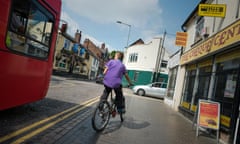 A boy cycling on the pavement in order to avoid a bus.