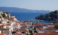 A view of terracotta tiled roofs on villas leading down to a harbour