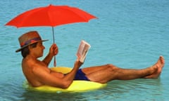 Middle-aged man with umbrella floating on tube in Caribbean reading book