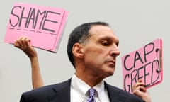 Protestors hold signs behind Dick Fuld as he takes his seat to testify at a House oversight and government reform committee hearing on the Lehman Brothers bankruptcy in Washington in October 2008