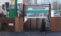 Two women in hijab walk past a Palestinian Lives Matter sign on a gate