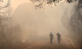 two people on a road walk through smoky air