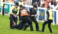 Police and security staff apprehend the protester.