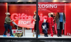 Staff attach a closing-down sign in a window of Debenhams store in Manchester