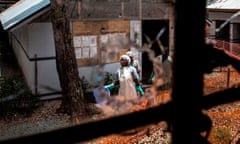 Health workers are seen through a bullet hole left in the window of an Ebola treatment centre in Butembo