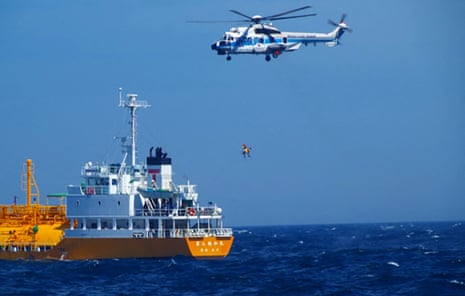 A Japanese coast guard helicopter lifts a woman to safety after she was swept out to sea off the southern tip of Chiba's Boso peninsula on Monday evening.