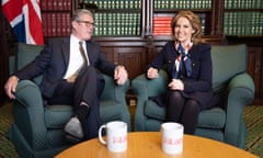 Keir Starmer and Natalie Elphicke sit in front of a packed bookcase in his office. A coffee table with two Labour mugs is in the foreground and there is a union flag behind them.