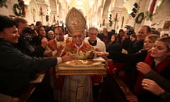 The Latin patriarch of Jerusalem, Fouad Twal, carries a statue of baby Jesus following the Christmas midnight mass at the Church of the Nativity, in Bethlehem.