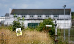 A fence with a sign saying 'you are on CCTV' with a building in the background