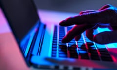 Silhouette of male hand typing on laptop keyboard at night