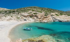 A deserted sandy cove with one small boat in the clear turquoise sea.