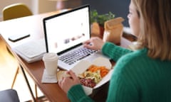 Woman eating takeaway food while working on her laptop.