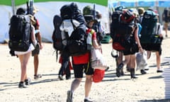 Scouts leaving the campsite of the World Scout Jamboree on dirt road with big backpacks