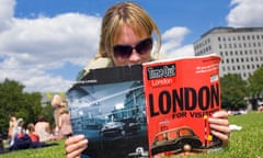 A woman reading Time Out magazine in a park