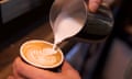 Close-up shot of a barista adding steamed milk to coffee