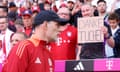 Thomas Tuchel looks on as a fan holds a sign saying 'Danke Tuchel'