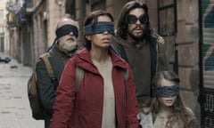 two men, a woman and a child, all wearing coats and eye masks in a deserted looking street