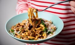 A fork pulling a tangle of pasta from a bowl of creamy mushroom fettuccine.