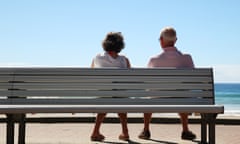 two retirees sit on bench looking out to sea