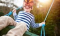 A boy playing on a garden swing wearing a mask