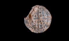 One side of the rusty metal token showing a pattern featuring a long cross dividing the surface into quarters