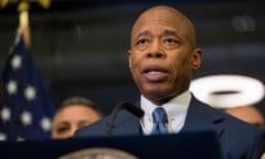 A man wearing a blue suit and tie speaks at a podium